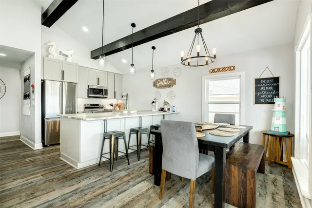 a kitchen with stainless steel appliances kitchen island granite countertop a dining table chairs refrigerator and sink