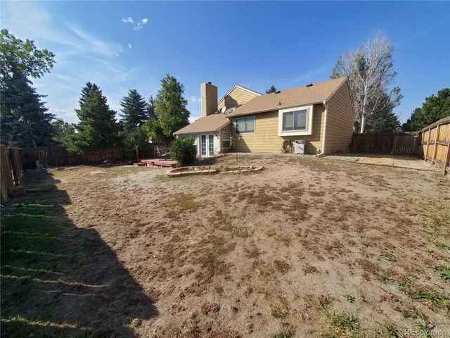 a view of a house with a yard and covered with trees