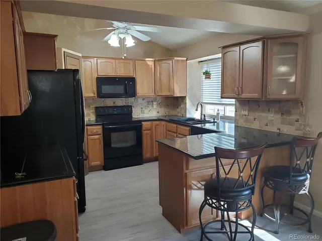 a kitchen with stainless steel appliances granite countertop a stove top oven a sink dishwasher a dining table and chairs with wooden floor