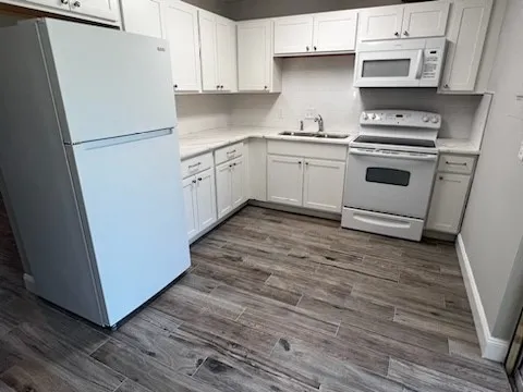 a kitchen with cabinets appliances and wooden floor