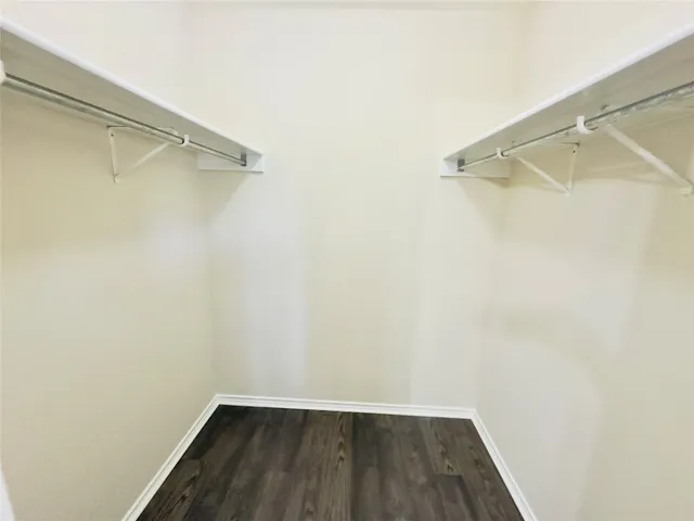 an empty room with wooden floor and fan