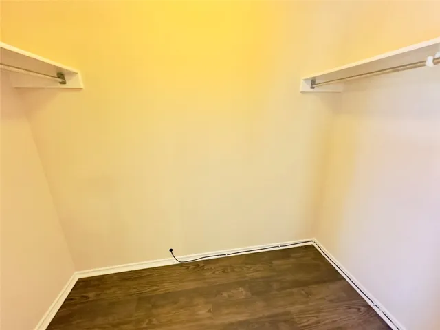an empty room with wooden floor and a hallway