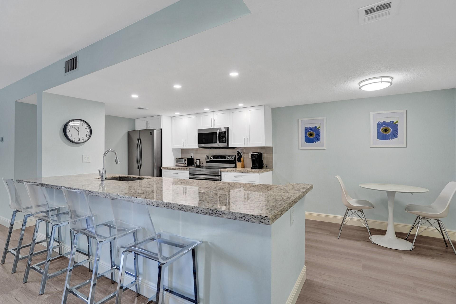 955 Dotterel Road, Unit 2304 Delray Beach, FL 33444 - Photo 2 of 47 a kitchen with stainless steel appliances granite countertop a sink a stove a dining table and chairs
