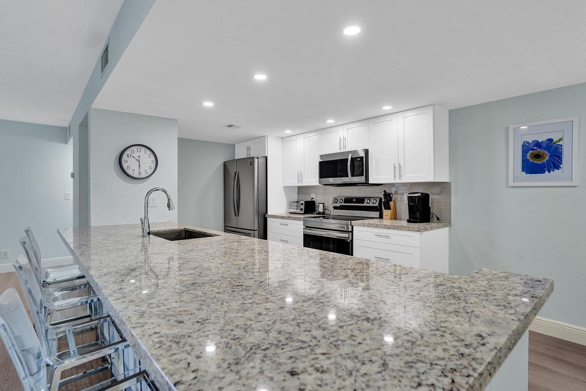 955 Dotterel Road, Unit 2304 Delray Beach, FL 33444 - Photo 29 of 47 a kitchen with stainless steel appliances granite countertop a sink refrigerator and microwave