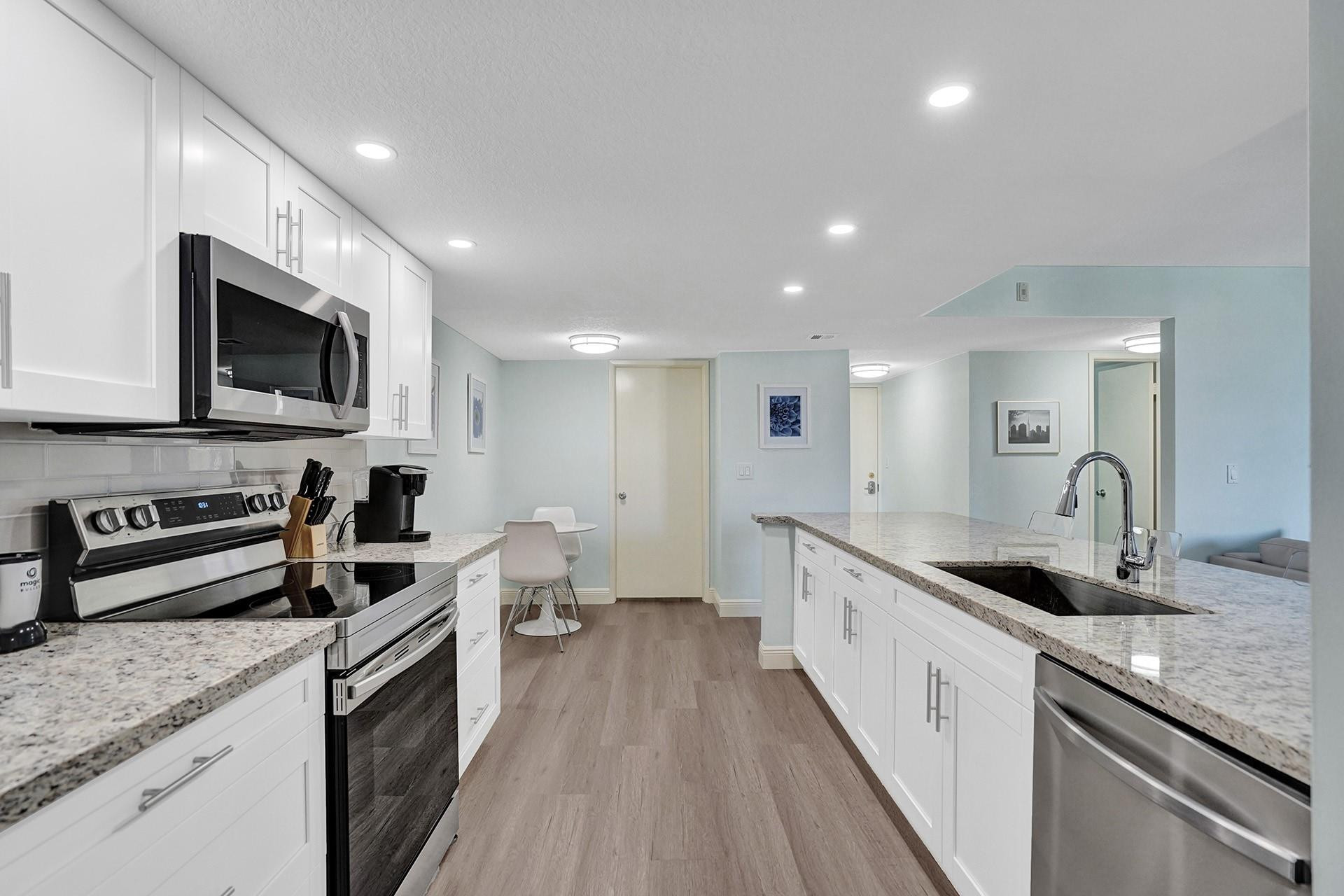 955 Dotterel Road, Unit 2304 Delray Beach, FL 33444 - Photo 35 of 47 a large kitchen with stainless steel appliances granite countertop a sink a stove top oven a granite counter tops and a view of living room
