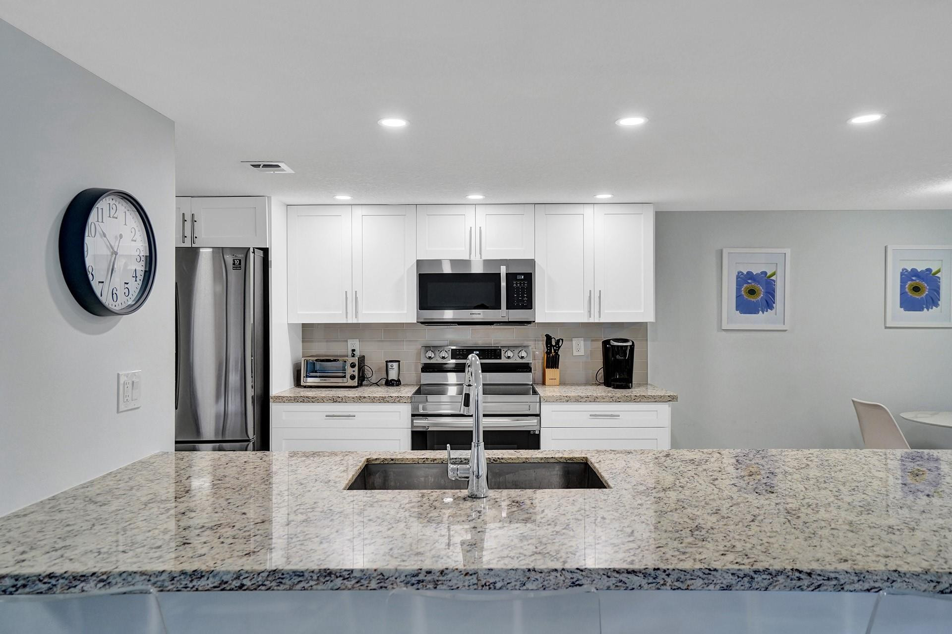 955 Dotterel Road, Unit 2304 Delray Beach, FL 33444 - Photo 44 of 47 a kitchen with stainless steel appliances granite countertop a sink a stove and a refrigerator