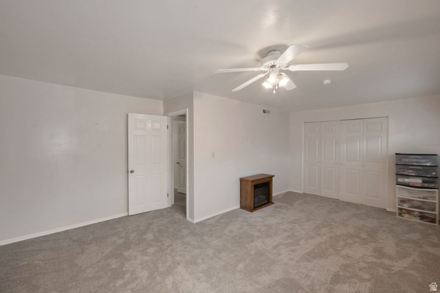 11072 Windy Peak Ridge Drive, Unit 32 Sandy, UT 84094 - Photo 28 of 30 Spacious room with light gray carpeting, white walls, and a white ceiling fan with integrated lighting