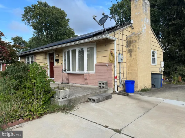 a view of a white house with large windows and potted plants