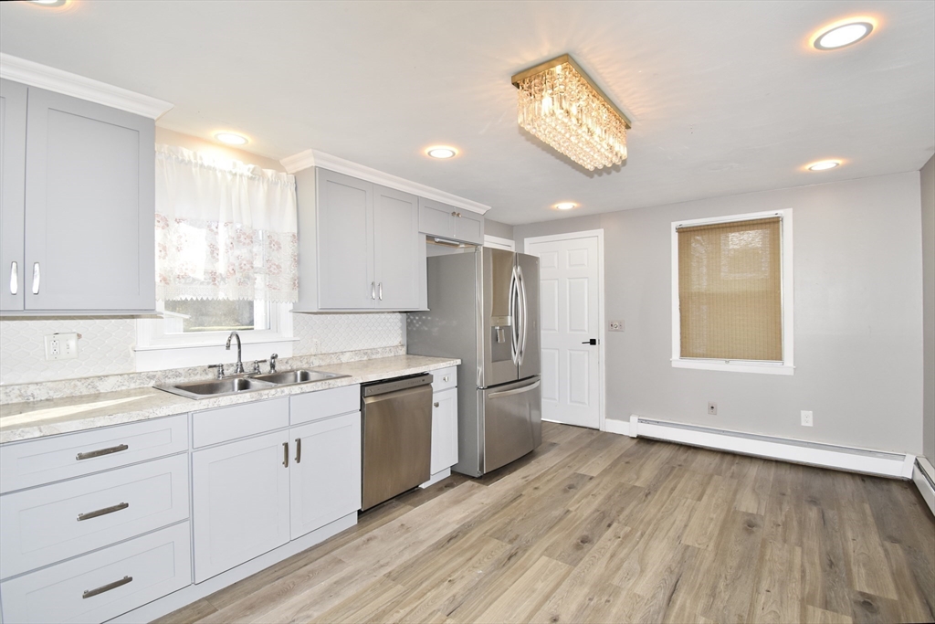 85 Orchard Street Chicopee, MA 01013 - Photo 5 of 33 a kitchen with a sink dishwasher a stove and white cabinets with wooden floor