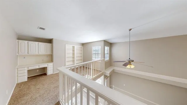 a view of an empty room with chandelier fan and windows