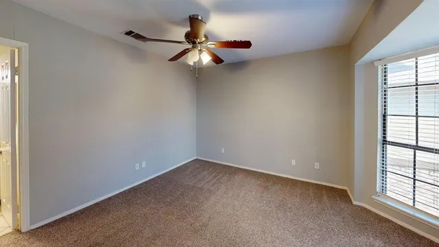an empty room with windows and fan