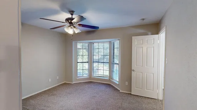 an empty room with windows and fan