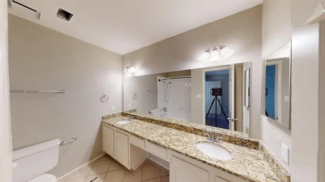 a bathroom with a granite countertop sink mirror vanity and toilet