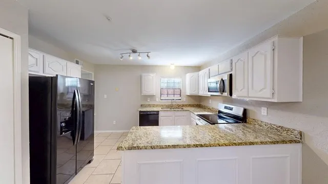 a kitchen with stainless steel appliances granite countertop a refrigerator a stove a sink and a granite counter tops