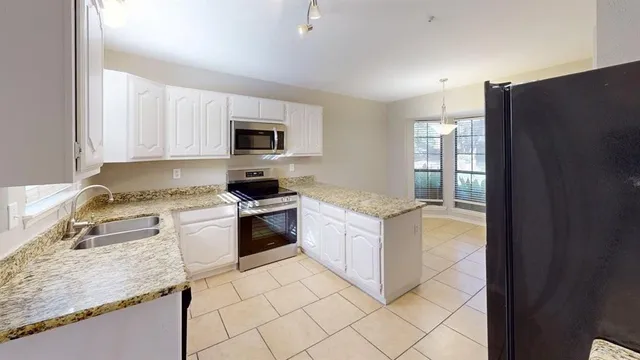 a kitchen with granite countertop white cabinets and stainless steel appliances