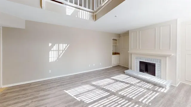a view of an empty room with wooden floor and a fireplace