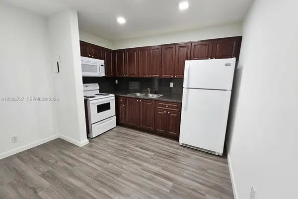 a kitchen with a refrigerator a stove top oven a sink and dishwasher with wooden floor