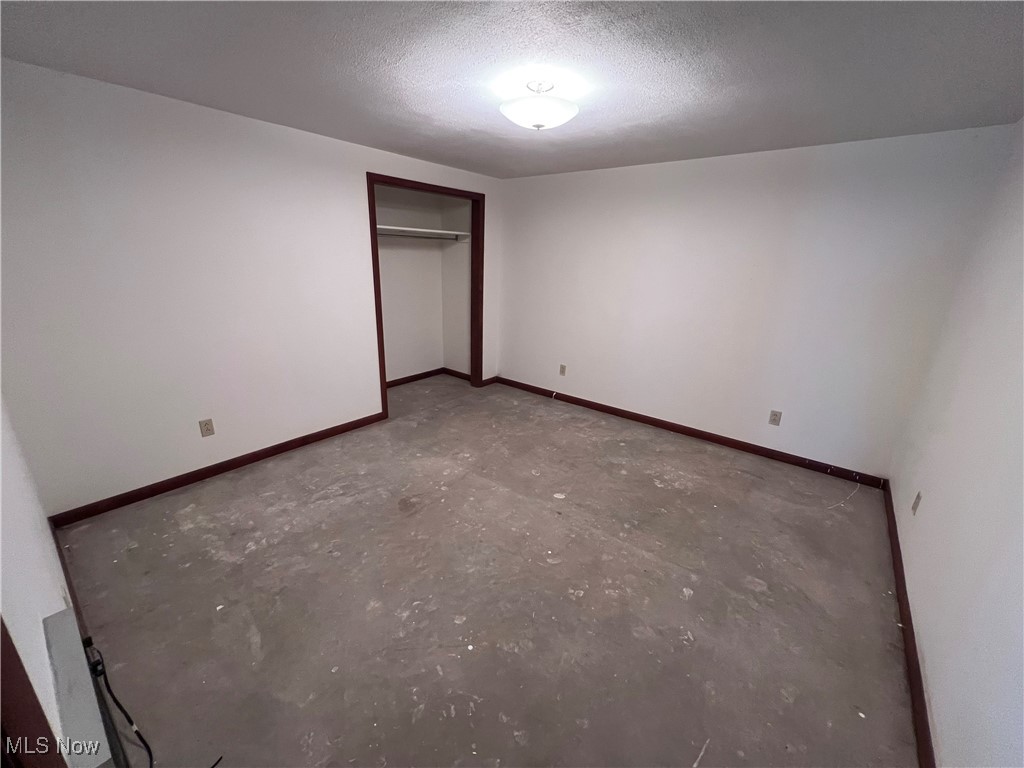 56376 Jordan Run Road Bellaire, OH 43906 - Photo 33 of 45 Unfurnished bedroom featuring a closet, concrete floors, and a textured ceiling