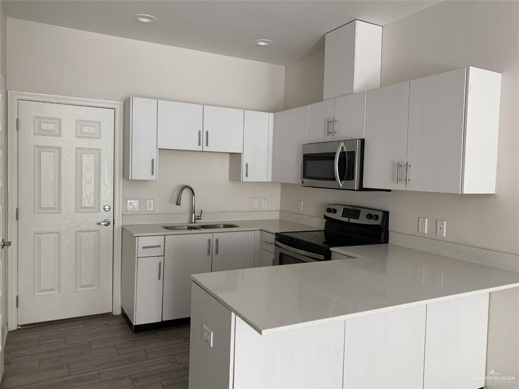 420 Teague Avenue, Unit 4 Edinburg, TX 78539 - Photo 2 of 14 a kitchen with kitchen island granite countertop a sink a stove a microwave oven a refrigerator white cabinets and wooden floor