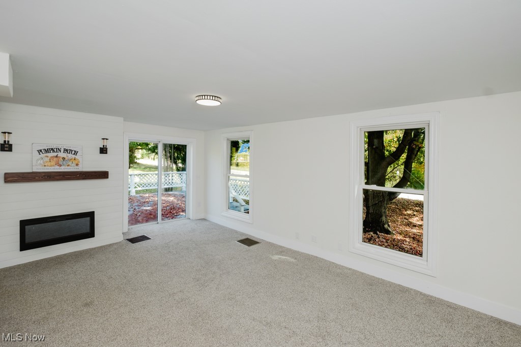 8150 Madison Road Thompson, OH 44086 - Photo 3 of 28 Unfurnished living room featuring carpet, healthy amount of natural light, and a fireplace