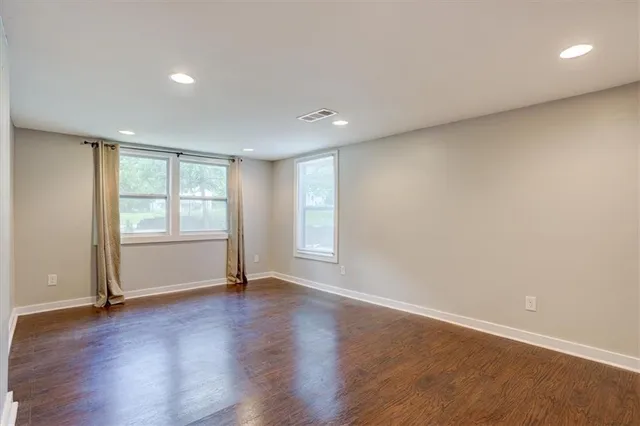 a view of an empty room with wooden floor and window