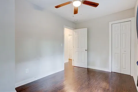 an empty room with wooden floor chandelier fan and closet area