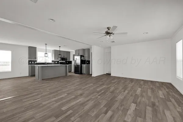 a view of kitchen and empty room with wooden floor