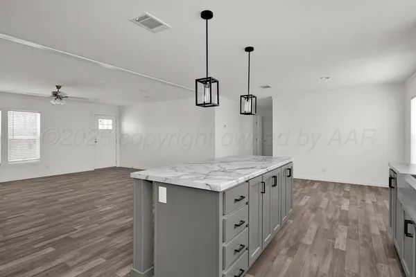 a kitchen with stainless steel appliances granite countertop a sink a stove a refrigerator a center island with wooden floor and cabinets