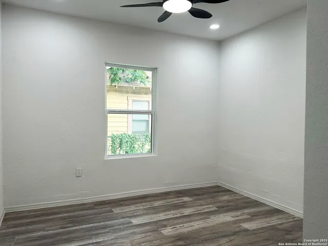 an empty room with a window and a ceiling fan