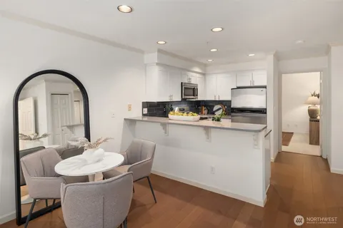 a living room with stainless steel appliances kitchen island granite countertop a dining table chairs and a refrigerator