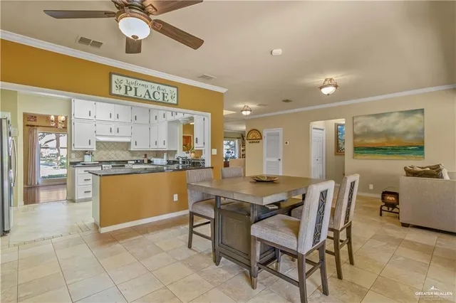 a kitchen with stainless steel appliances kitchen island granite countertop a table chairs sink and cabinets
