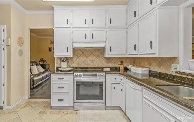 a kitchen with granite countertop white cabinets and stainless steel appliances