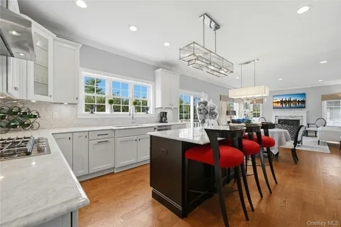 a kitchen with stainless steel appliances granite countertop a stove top oven a sink a dining table and chairs with wooden floor