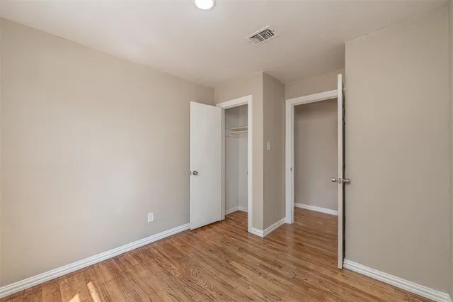 a view of an empty room with wooden floor and closet