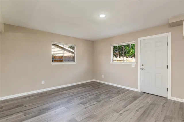 a view of an empty room with wooden floor and a window
