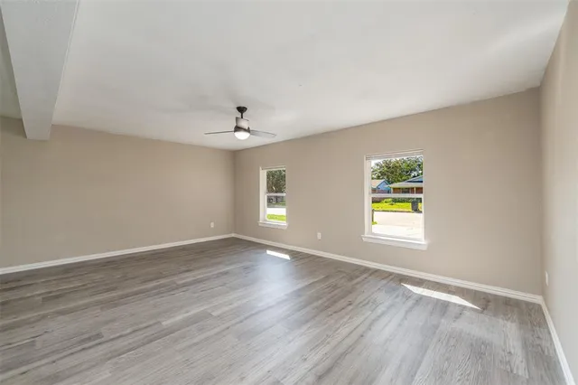 a view of an empty room with a window and wooden floor