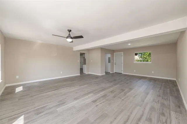 a view of an empty room with a window and a ceiling fan