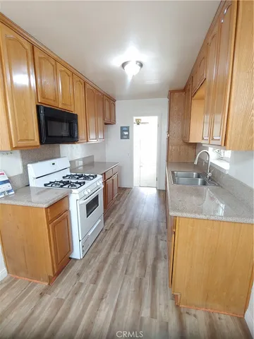 a kitchen with granite countertop wooden floors a stove and a microwave