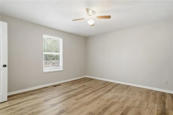 an empty room with wooden floor and fan