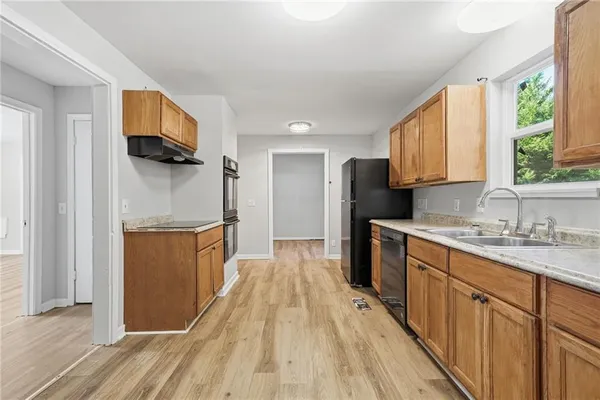 a kitchen with stainless steel appliances granite countertop a refrigerator a sink dishwasher a stove with wooden cabinets and floor