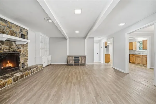 a view of an empty room with wooden floor fireplace and a window