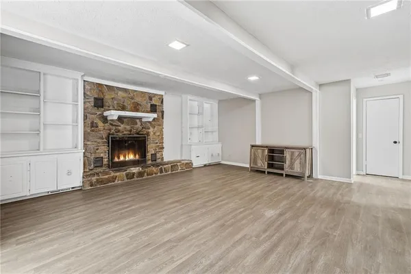 an empty room with wooden floor fireplace and windows