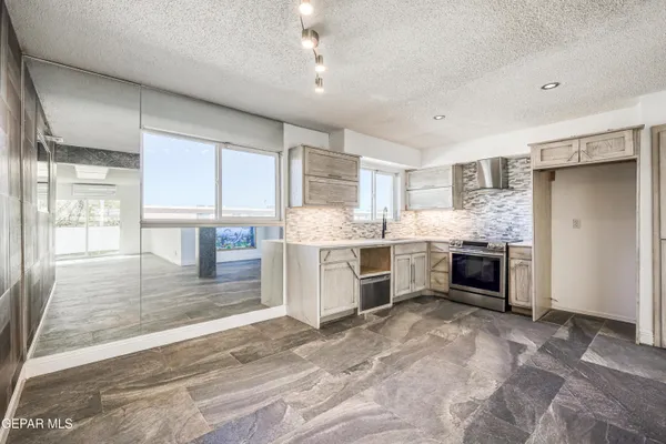 a kitchen with stainless steel appliances kitchen island granite countertop a stove refrigerator and cabinets