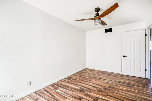 an empty room with windows and ceiling fan