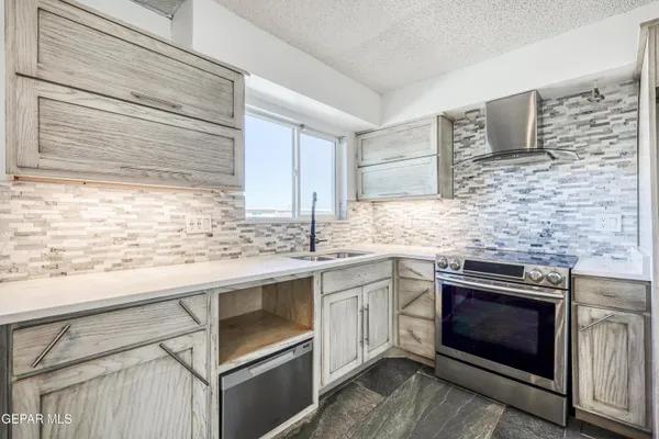 a kitchen with granite countertop stainless steel appliances a sink window and cabinets
