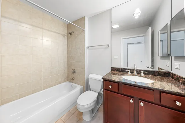 a bathroom with a granite countertop sink toilet vanity mirror bathtub and shower