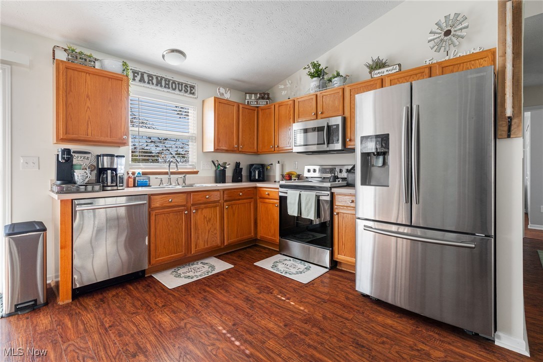 64 River Ridge Lane Munroe Falls, OH 44262 - Photo 10 of 25 Kitchen with appliances with stainless steel finishes, a textured ceiling, dark wood-type flooring, lofted ceiling, and light countertops