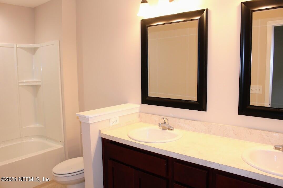 4148 Quiet Creek Loop, Unit 132 Middleburg, FL 32068 - Photo 30 of 42 a bathroom with a granite countertop sink toilet and shower