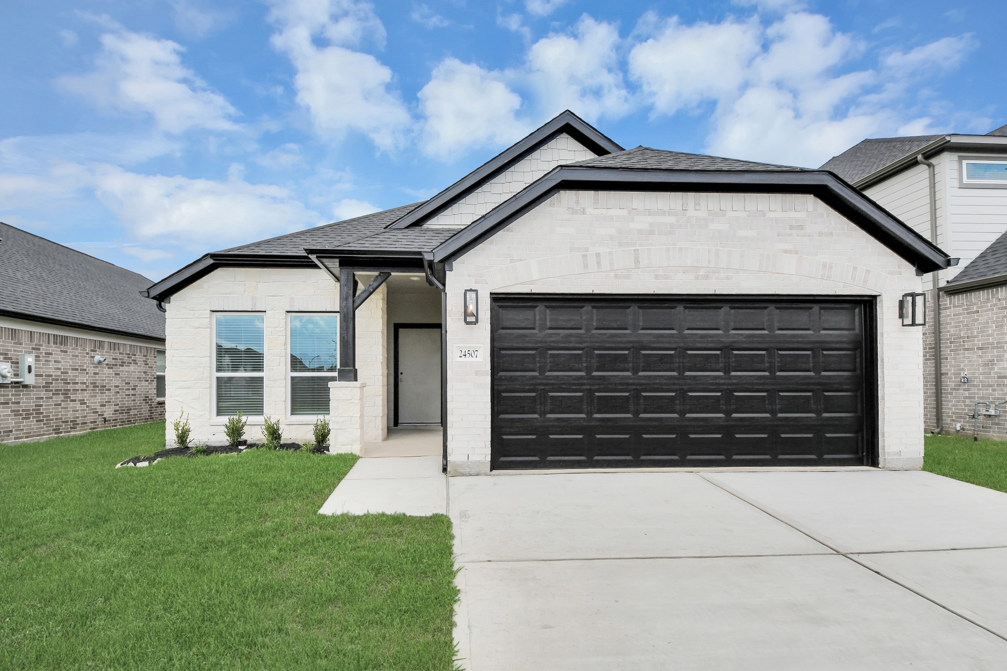 24507 Broad Park Spring, TX 77373 - Photo 3 of 37 Meticulously maintained yard and lush landscape, paired with a premium elevation featuring captivating brick accents. Modern coach lights add a touch of contemporary elegance to the exterior.