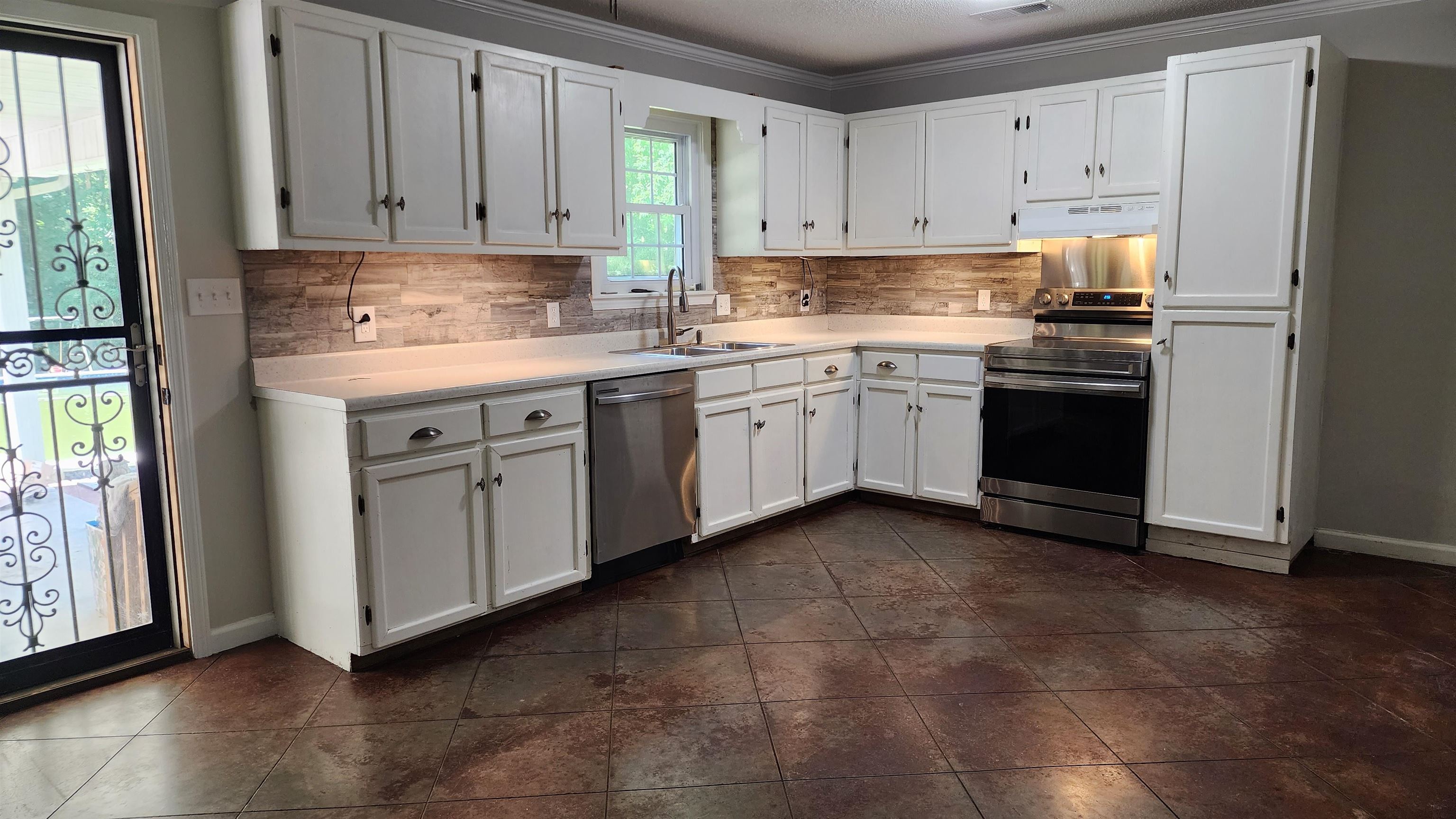 445 Caldwell Road Ripley, TN 38063 - Photo 5 of 14 Kitchen featuring stainless steel appliances, a sink, under cabinet range hood, white cabinetry, and ornamental molding